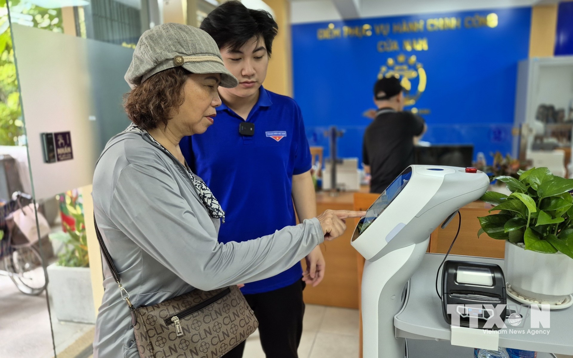 Người dân thực hiện thao tác trên robot AI thực hiện các thủ tục hành chính tại phường Cửa Nam, Hà Nội. (Ảnh: Nguyễn Thắng/TTXVN)